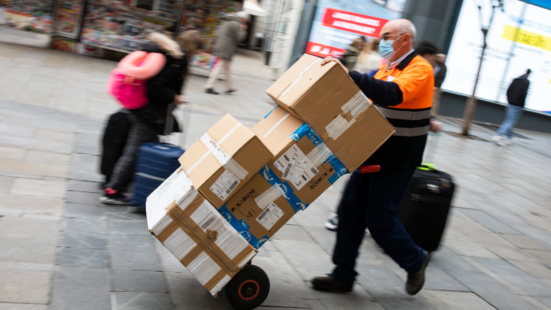 Un repartidor de mercancías con un carro lleno de cajas por el centro de Madrid