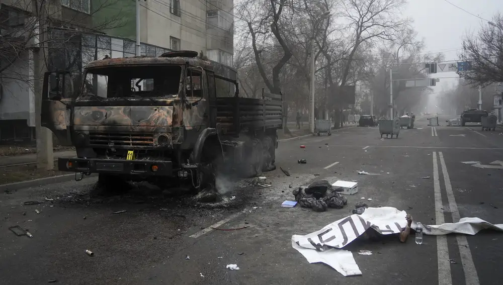 El cuerpo de una víctima yace en el suelo, al lado de un carro de combate incendiado durante los disturbios de esta semana en Almaty