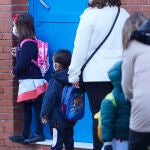 Varios niños esperan la apertura de la puerta de su colegio en Sevilla durante la vuelta tras las vacaciones de Navidad con la aplicación de las nuevas restricciones dependiente de cada comunidad autónoma