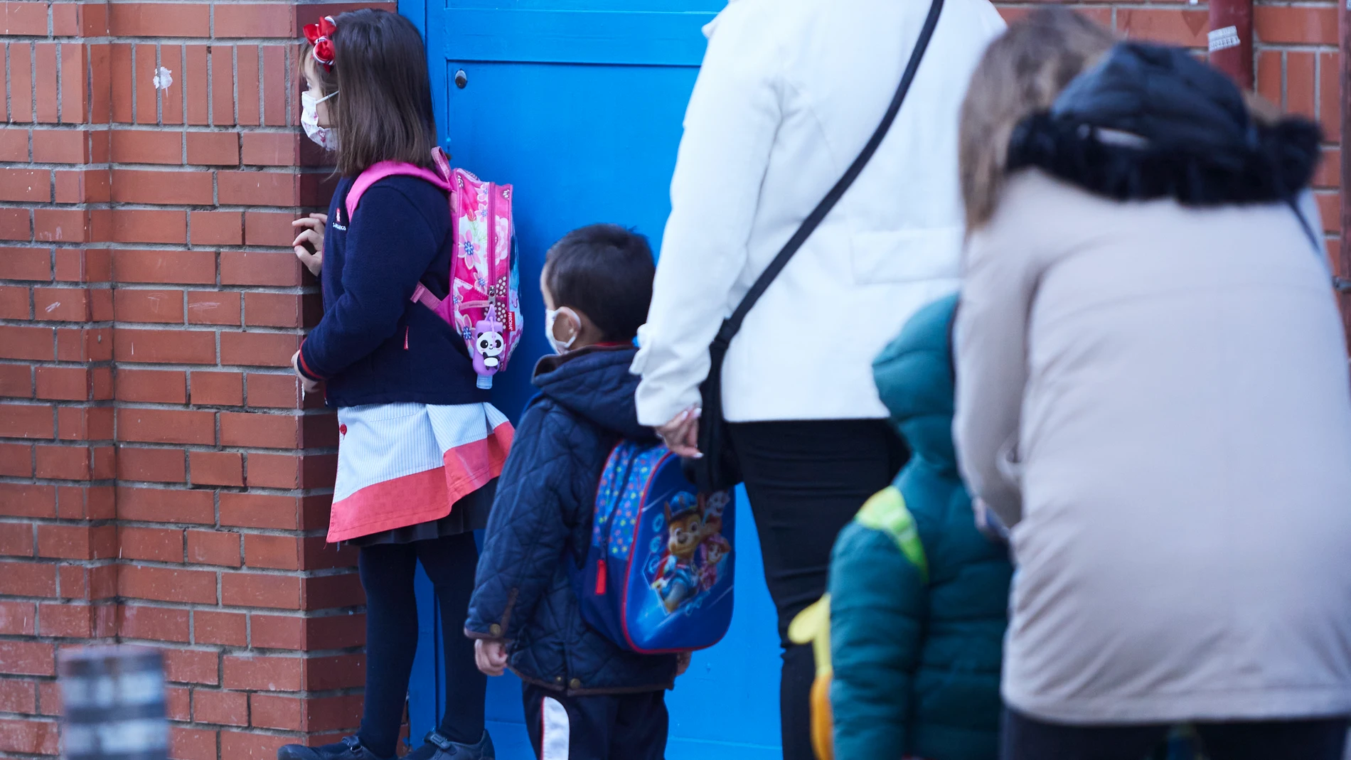 Varios niños esperan la apertura de la puerta de su colegio en Sevilla durante la vuelta tras las vacaciones de Navidad con la aplicación de las nuevas restricciones dependiente de cada comunidad autónoma