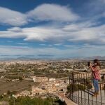 Una mujer hace una foto a la huerta con la ciudad de Murcia al fondo