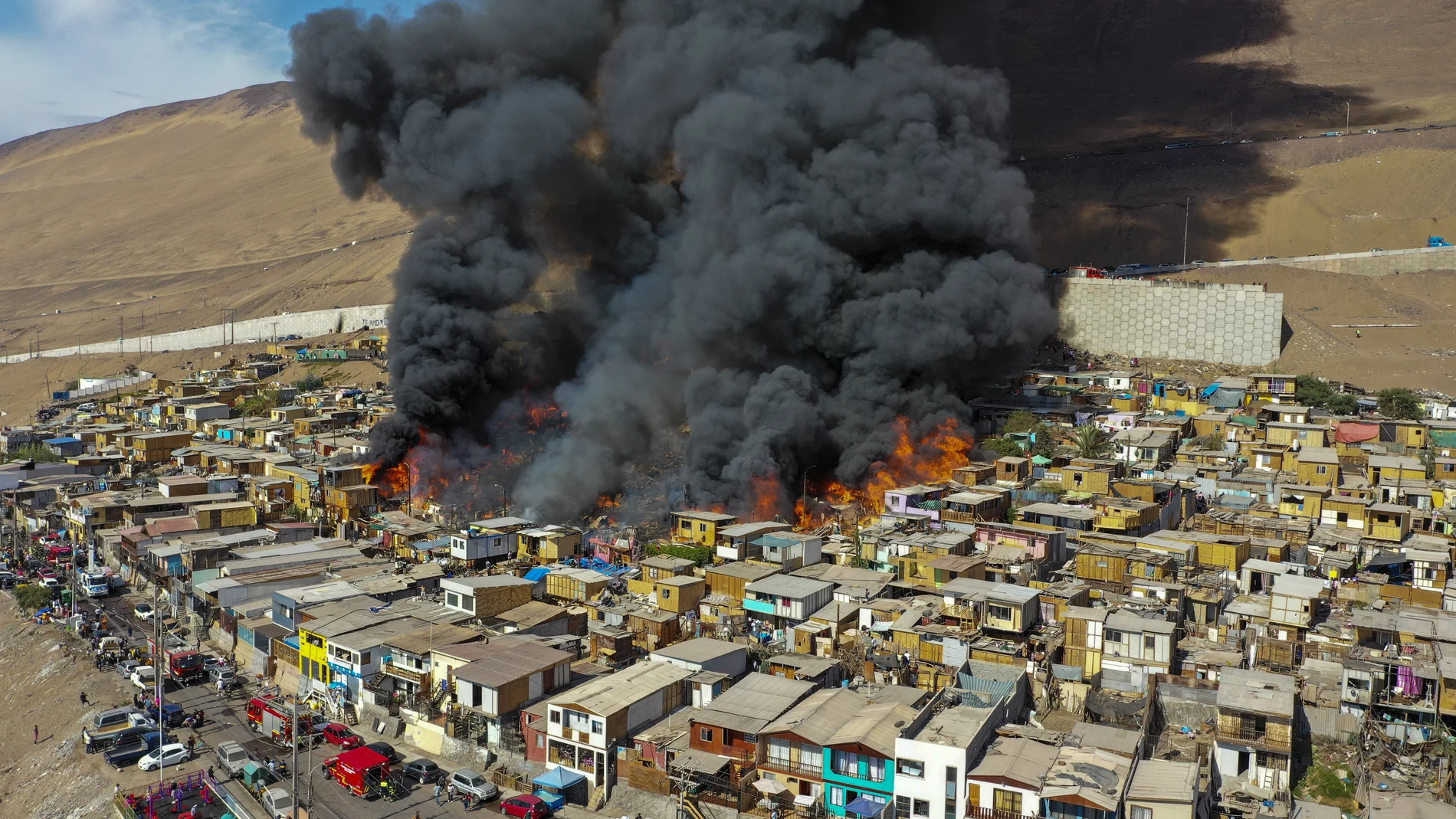 Houses burn during a fire in the low income neighborhood of Laguna Verde, in Iquique, Chile, Monday, Jan. 10, 2022. According to authorities the fire destroyed close to 100 homes of the neighborhood which is populated mostly by migrants. (AP Photo/Ignacio Munoz)