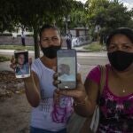 Servilia Pedroso, a la derecha, madre del estudiante de 18 años Eloy Barbaro Cardoso, y Yaquelin Cruz, madre de Dariel Cruz, muestran las fotos de sus arrestados durante las protestas del 11 de julio, frente al edificio del tribunal donde están siendo juzgados en La Habana, Cuba