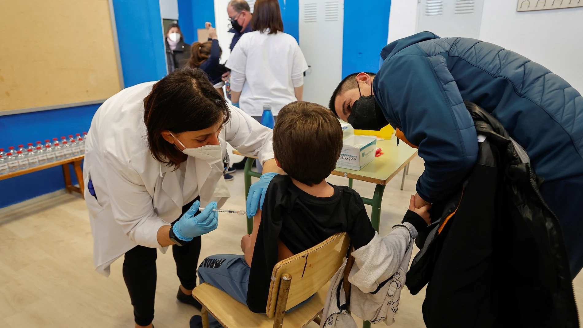 Un padre acompaña a su hijo mientras la vacunan en el CEIP Blasco de Alagón de Vilafranca (Castellón) durante el inicio de la segunda fase de la campaña de vacunación pediátrica, a 13 de enero de 2022