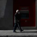 Una persona mayor pasa frente a un cajero del Banco Santander
