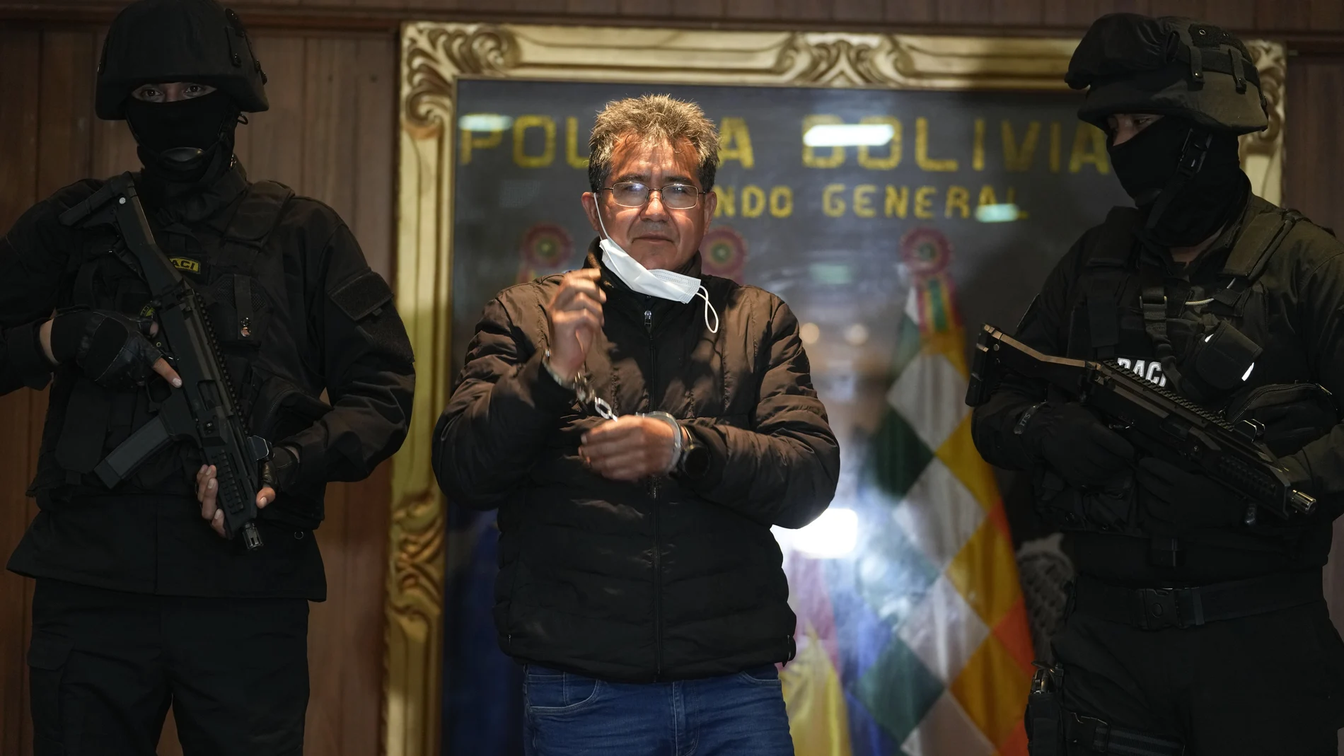 Police escort former police colonel Maximiliano Davila, center, as he was presented to the media at a Bolivian Police Command office, in La Paz, Bolivia, Sunday, Jan. 23, 2022. Authorities announced the capture of Colonel Davila, the former anti-drug director of the Bolivian police, for being tied to a wide drug trafficking ring. (AP Photo/Juan Karita)