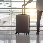 Un hombre lleva una maleta de mano en un aeropuerto