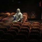 Un empleado sanitario desinfecta los asientos de una sala de cine