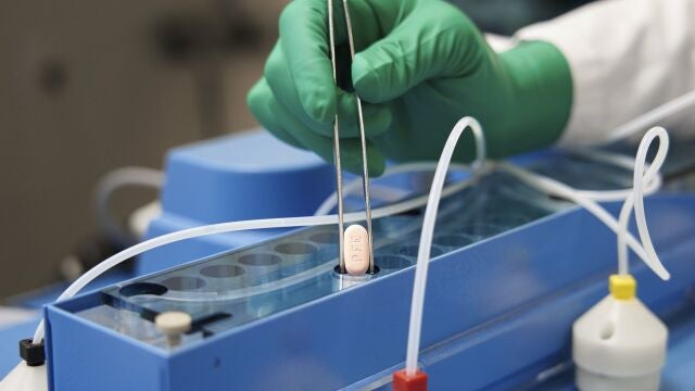 Un técnico de laboratorio de la farmacéutica Pfizer manipula una cápsula de las dos que integran el nuevo tratamiento antiviral contra la covid, Paxlovid
