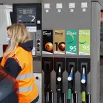 Una empleada de una gasolinera, surte combustible a un vehículo