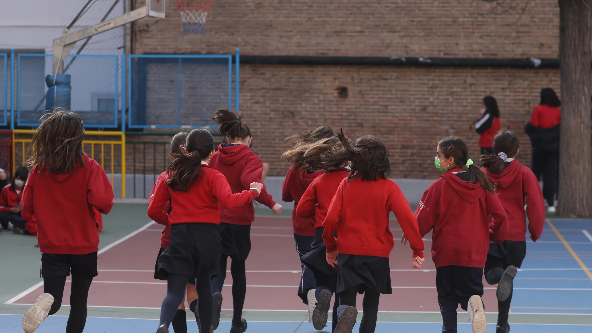 Un grupo de niños corren en el patio del colegio