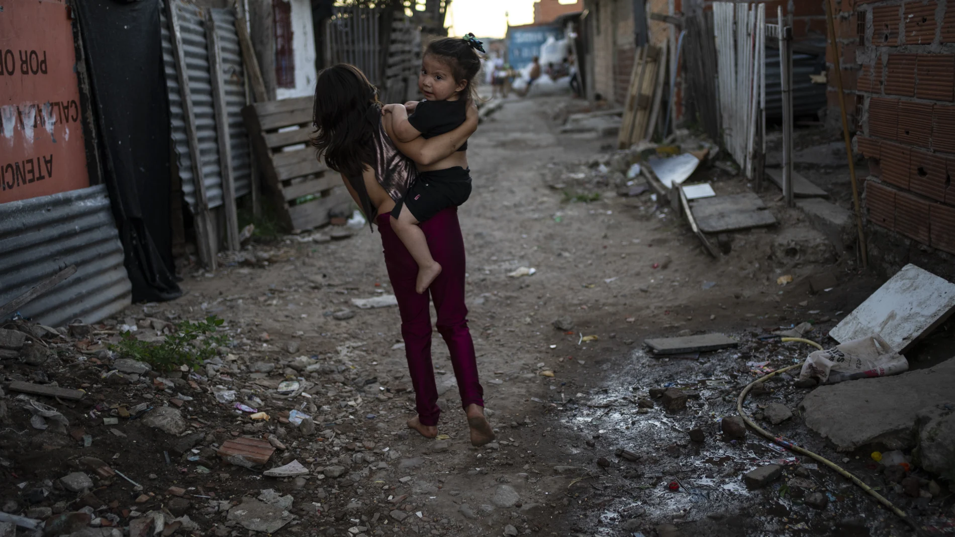 Una joven lleva un bebé a cuestas en el deprimido suburbio Puerta 8 de Buenos Aires