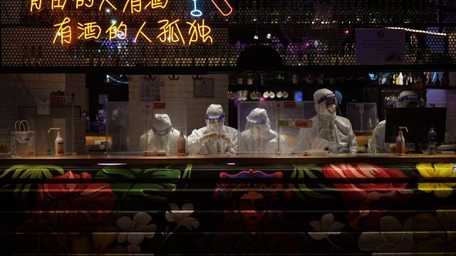 Camareros con trajes protectores y mascarillas para protegerse de la COVID-19 trabajan en un hotel en los Juegos Olímpicos de Invierno de 2022
