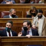 El portavoz de Vox en el Congreso, Iván Espinosa de los Monteros, conversa con el líder del partido, Santiago Abascal, en presencia de la portavoz adjunta Macarena Olona durante la sesión plenaria del Congreso de los Diputados. EFE/ Mariscal