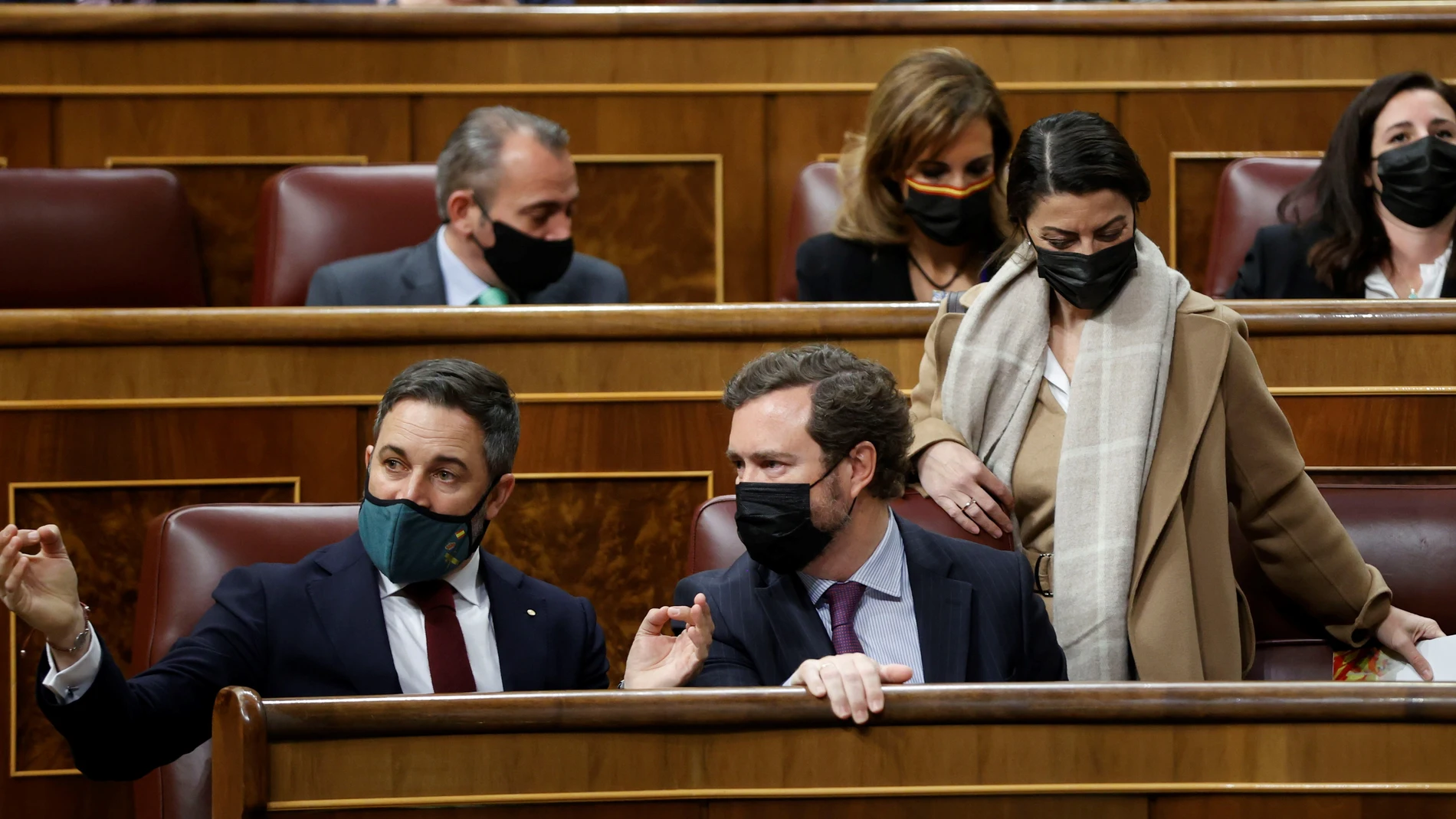 El portavoz de Vox en el Congreso, Iván Espinosa de los Monteros, conversa con el líder del partido, Santiago Abascal, en presencia de la portavoz adjunta Macarena Olona durante la sesión plenaria del Congreso de los Diputados. EFE/ Mariscal