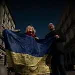 Iryna Martynovska (derecha) e Ivan Vovk (izquierda) sostienen una bandera de Ucrania firmada por miembros de las tropas desplegadas del Ejército ucraniano en la frontera, en la Puerta del Sol de Madrid (España).