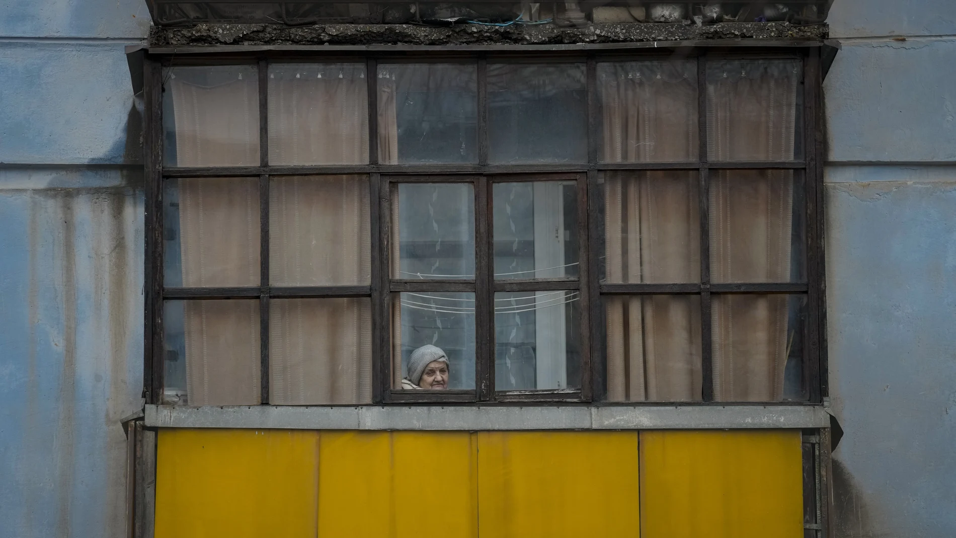 Una mujer mira por la ventana de su apartamento en Sievierodonetsk, en la región de Lugansk controlada por el gobierno ucraniano.