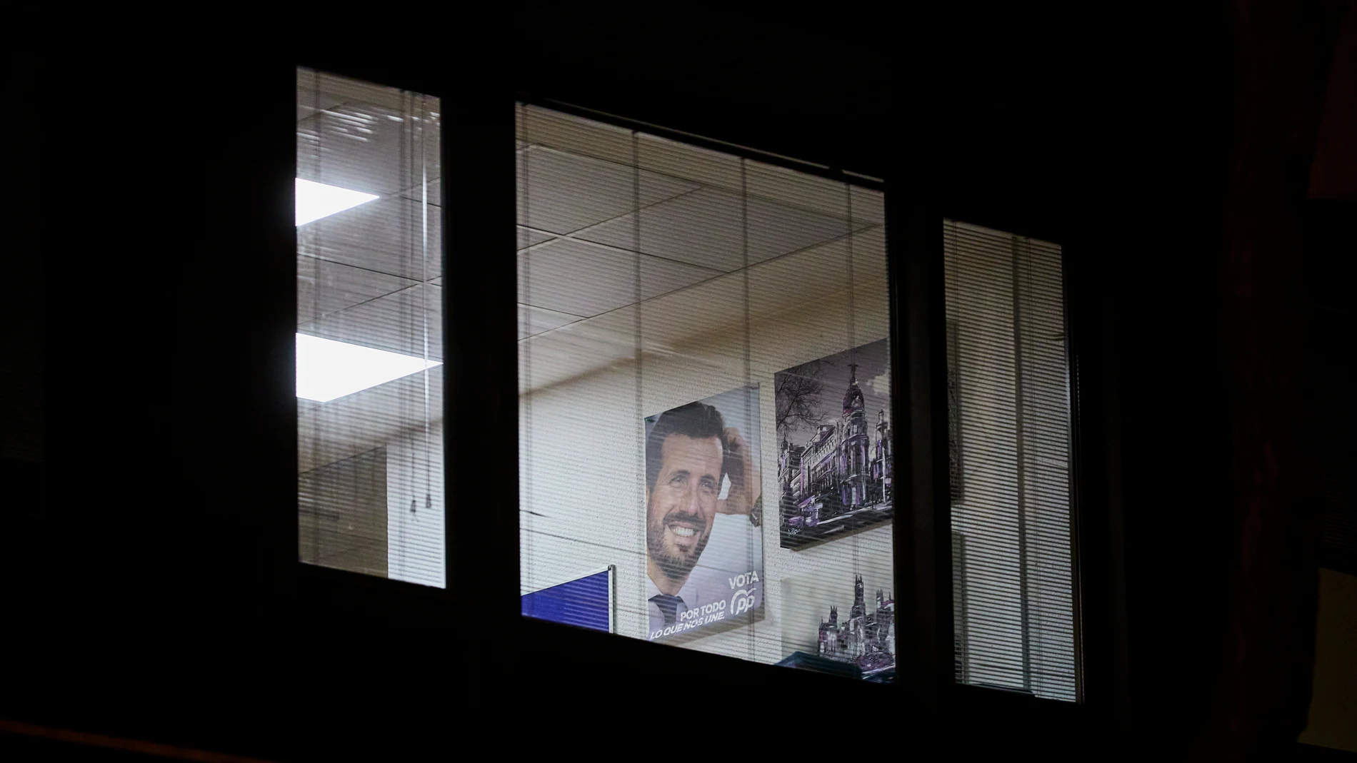Un cartel electoral del líder del Partido Popular, Pablo Casado, se muestra a través de las ventanas, en las oficinas de la sede del PP en la calle Génova