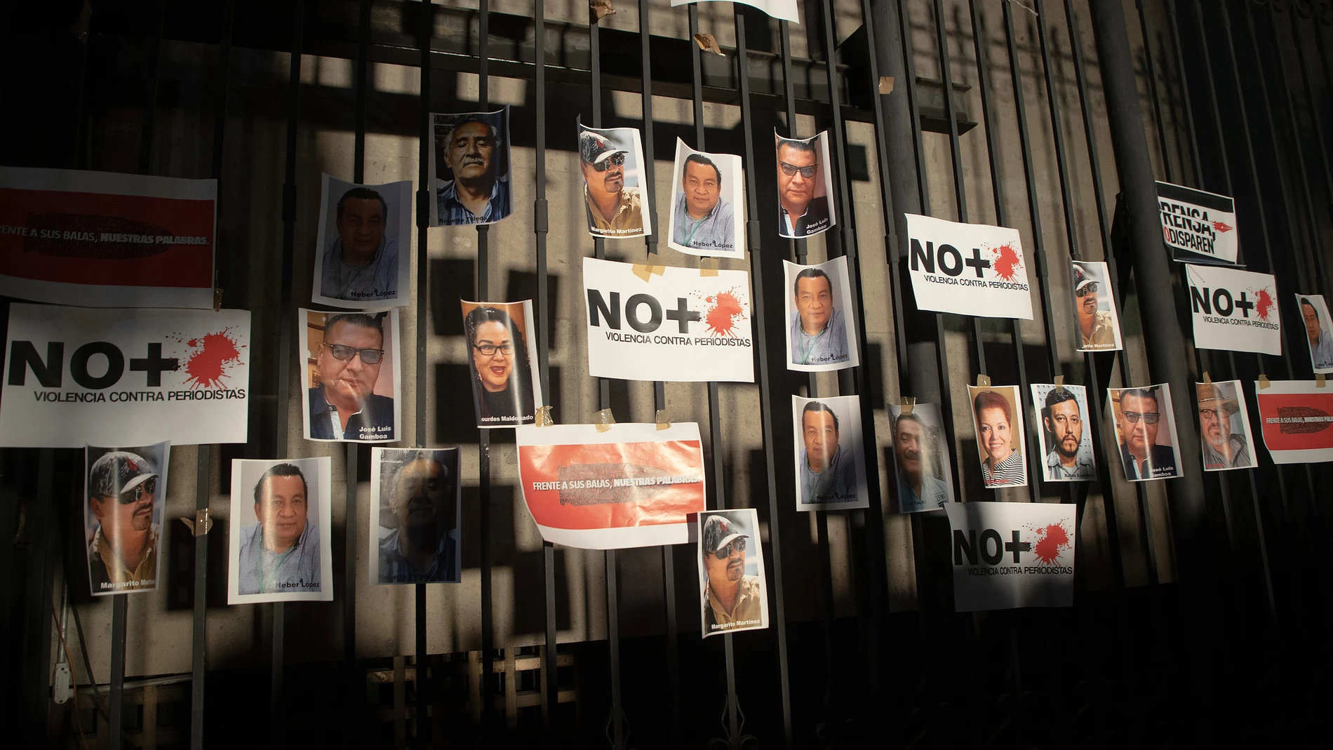Periodistas pegan fotografías de compañeros asesinados como protesta, en una valla en la Secretaria de Gobernación (SG), el 14 de febrero de 2022.