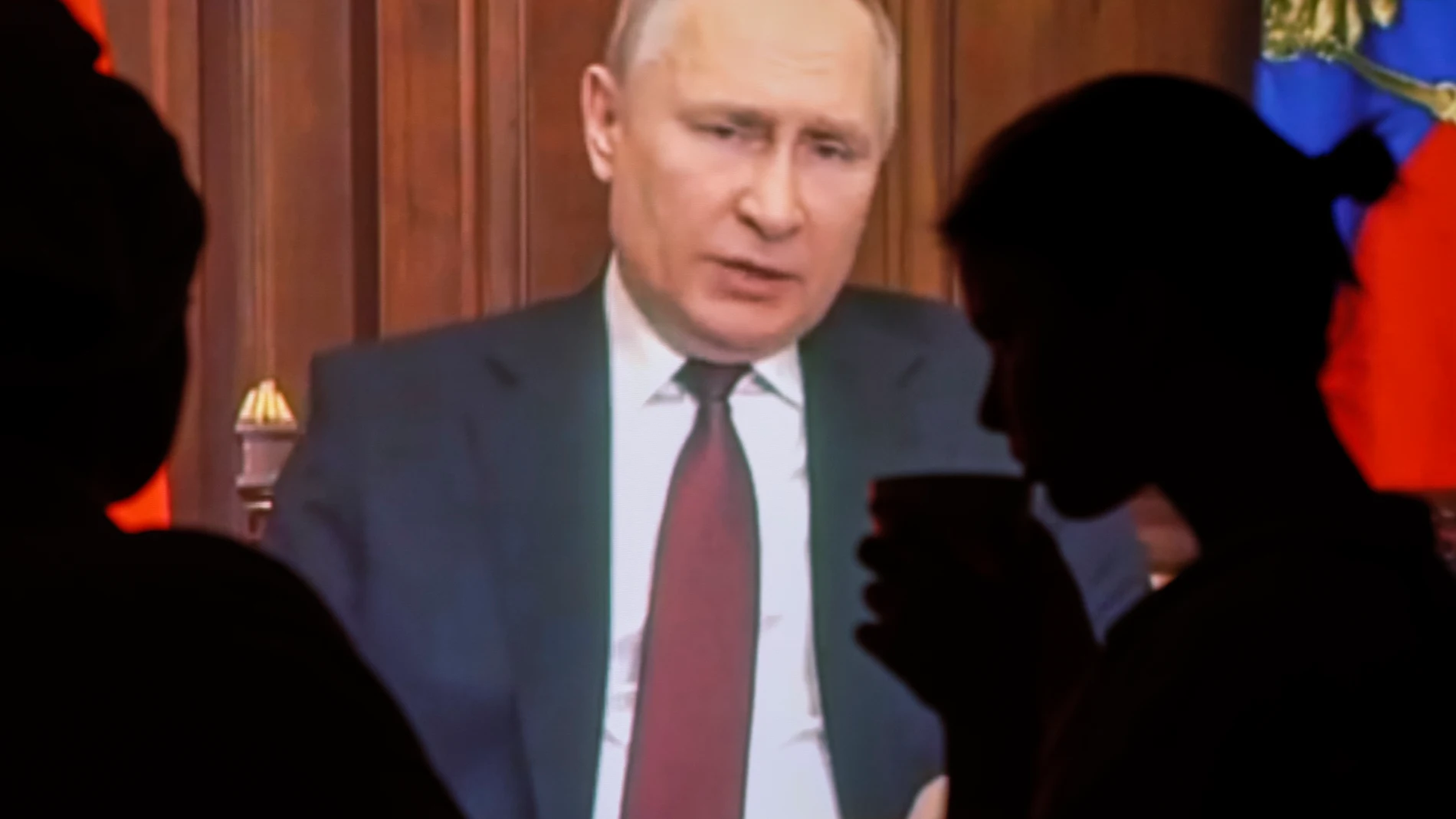 Dos personas observan el discurso televisado del presidente ruso Vladimir Putin en Moscú