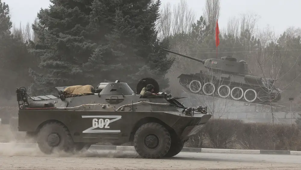 Un vehículo blindado con la letra 'Z' pasa por un monumento que muestra un tanque de la era soviética