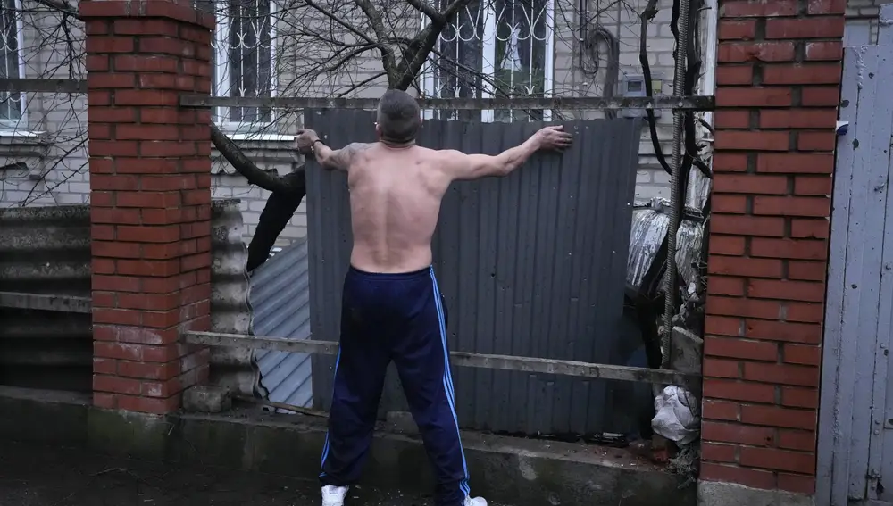 Un hombre reinstala una cerca después de un bombardeo ruso en Mariupol, Ucrania