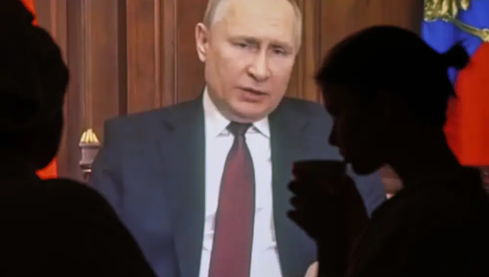 Dos personas observan el discurso televisado del presidente ruso Vladimir Putin en Moscú | Fuente: EFE/ Sergei Ilnitsky