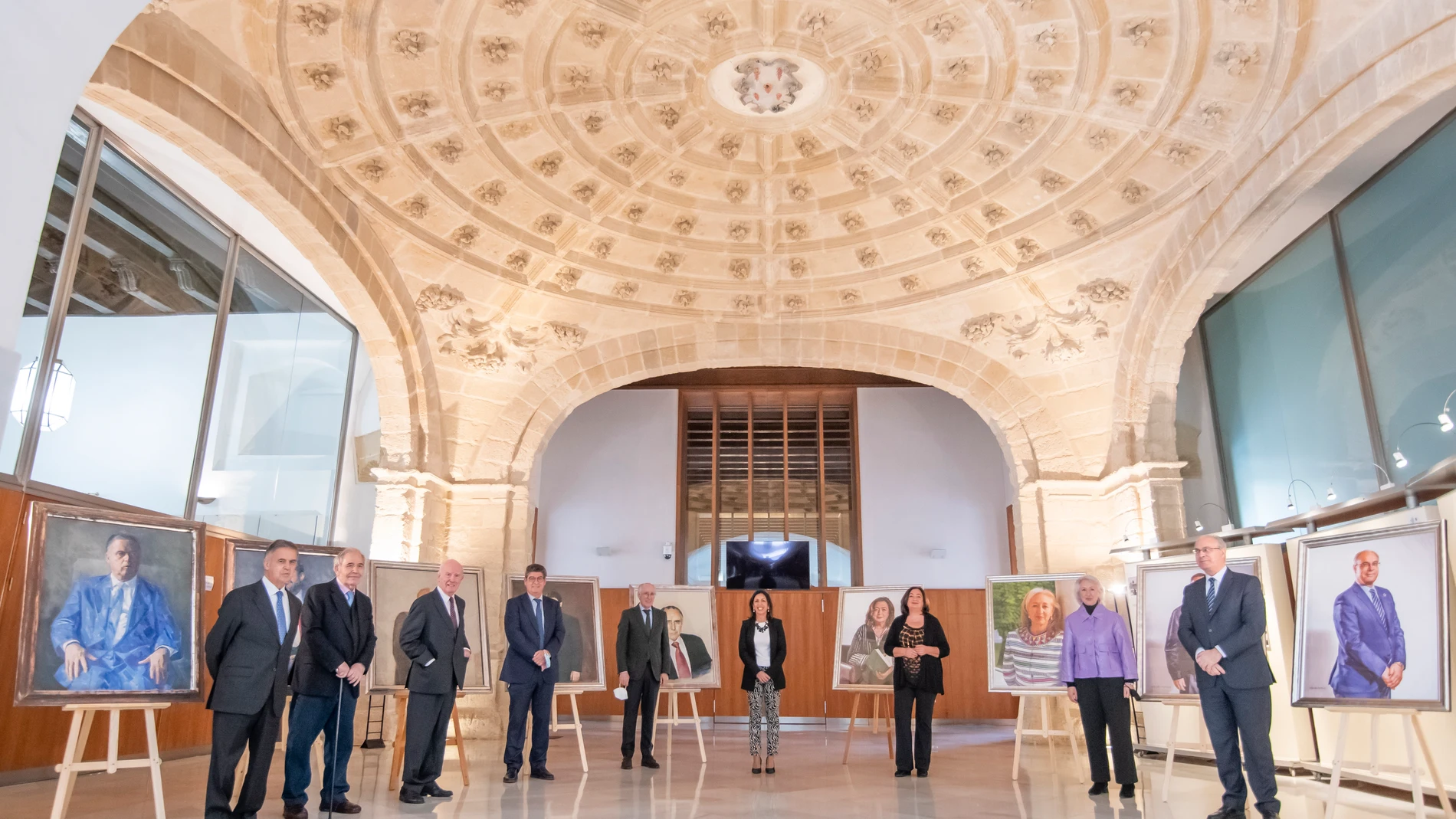 La presidenta del Parlamento de Andalucía, Marta Bosquet (c), junto a ocho de los nueve expresidentes de la Cámara, durante el acto donde se han presentado los retratos de María del Mar Moreno (3d), Fuensanta Coves (2d), Manuel Gracia (ausente) y Juan Pablo Durán (d)./ Raúl Caro.