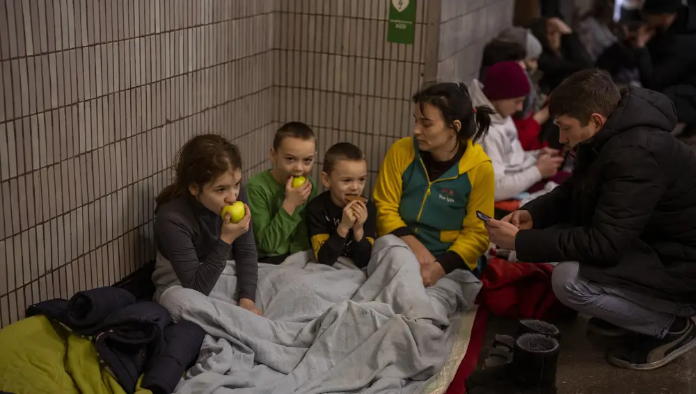 Una familia sentada en el metro de Kiev, usado como refugio antiaéreo