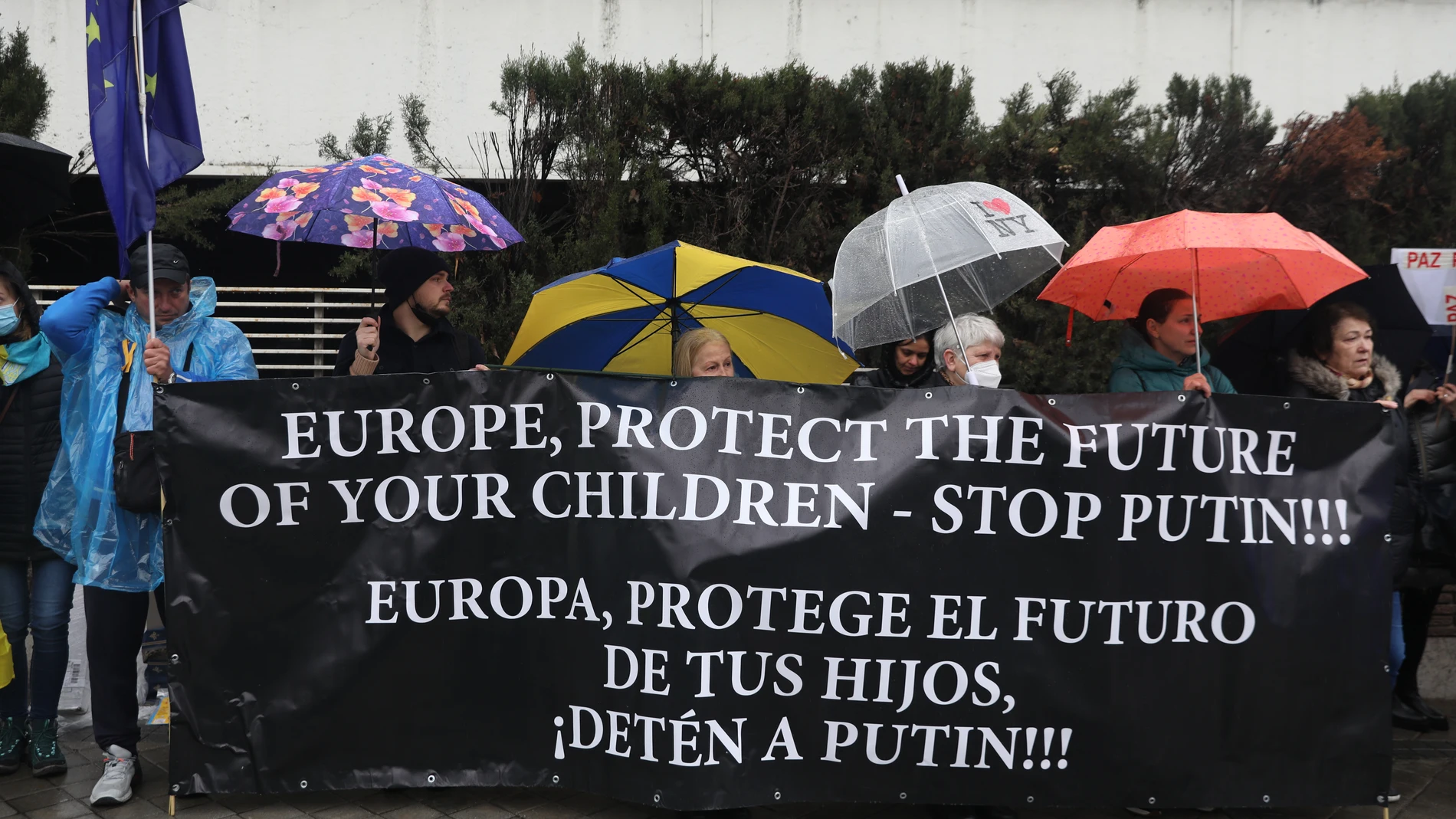 Un grupo de personas con una pancarta que reclama que se paralice a Putin, participan en una nueva concentración ante la embajada rusa de Madrid tras los ataques