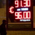 Un hombre camina frente a un panel digital que muestra el tipo de cambio del euro en una oficina de cambio en San Petersburgo, Rusia,