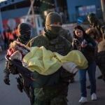 Un soldado eslovaco lleva a un bebé en un asiento de automóvil mientras personas que huyen de Ucrania llegan a Eslovaquia, en el cruce fronterizo de Vysne Nemecke,