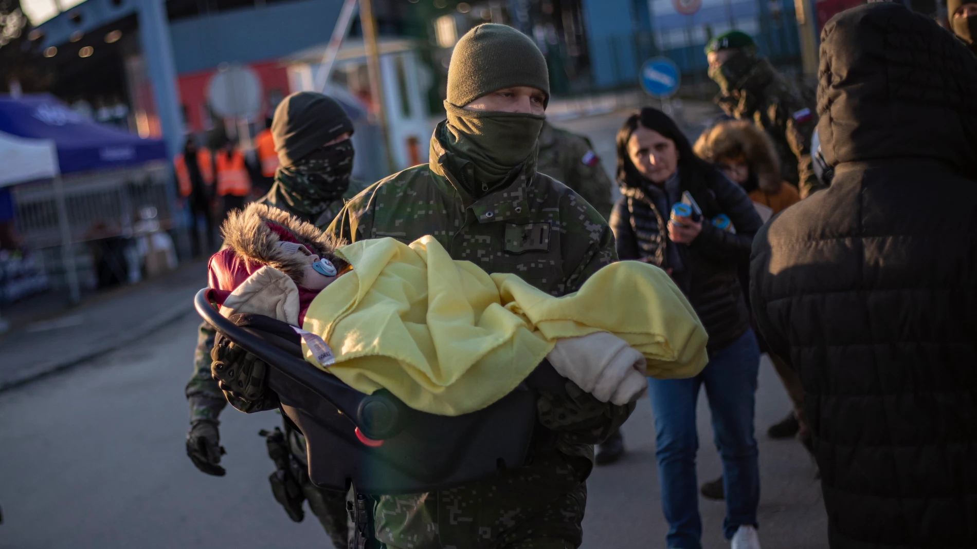 Un soldado eslovaco lleva a un bebé en un asiento de automóvil mientras personas que huyen de Ucrania llegan a Eslovaquia, en el cruce fronterizo de Vysne Nemecke,