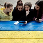 Cuatro estudiantes miran las noticias en un teléfono móvil en un centro de acogida cuando la guerra en Ucrania las ha sorprendido de viaje en España