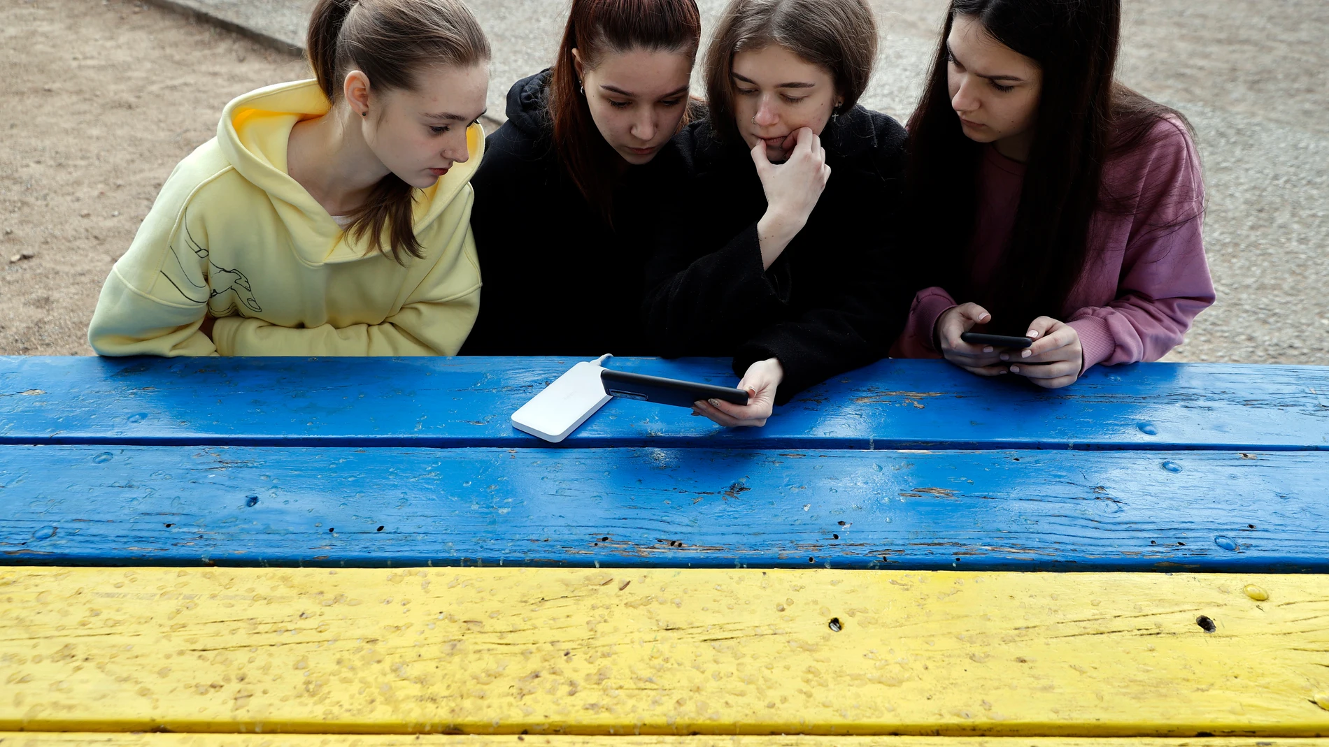 Cuatro estudiantes miran las noticias en un teléfono móvil en un centro de acogida cuando la guerra en Ucrania las ha sorprendido de viaje en España