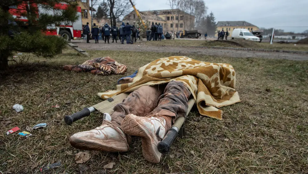 El cuerpo de una persona yace en el suelo junto a un edificio militar que, según las fuerzas terrestres ucranianas, fue destruido por un ataque aéreo, en la región de Sumy