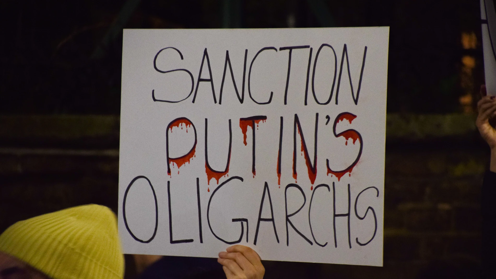 Un manifestante sostiene una pancarta "Sancionar a los oligarcas de Putin". Manifestantes reunidos frente a la embajada rusa en Londres en protesta por la invasión rusa de Ucrania. 05/03/2022
