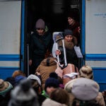 Varias personas suben a un tren en la estación de tren de Lviv (Ucrania) para huir del conflicto bélico