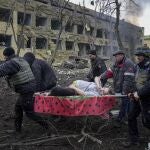 Empleados y voluntarios de emergencia ucranianos llevan a una mujer embarazada herida desde el hospital de maternidad destruido por los bombardeos en Mariúpol