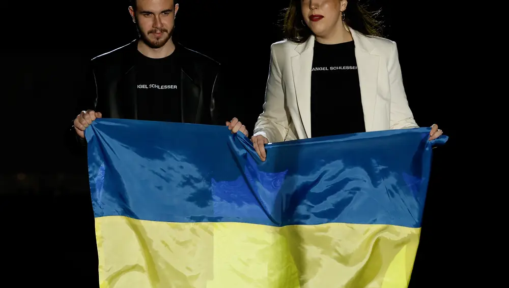 Cristina Munuera y Jaime Beltrán, los diseñadores de la firma Angel Schlesser portan una bandera de Ucrania al final del desfile durante la 75 edición de la Mercedes-Benz Fashion Week Madrid, este sábado en el recinto ferial Ifema de la capital.