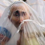 Un "ninot" que representa al presidente de Rusia, Vladimir Putin, es protegido con plásticos ante la amenaza de lluvia durante el montaje de las fallas de valencia