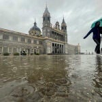Dos mujeres caminan bajo la lluvia provocada por la borrasca Celia junto a la catedral de La Almudena en Madrid este lunes