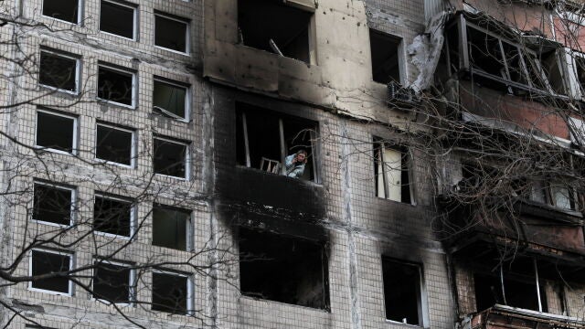 Una residente se asoma a la ventana de un edificio destruido por un bombardeo ruso en Kiev (Ucrania), este lunes. EFE/ Miguel A. Lopes