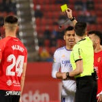 El delantero brasileño del Real Madrid Vinícius Jr (2i) y el delantero del RCD Mallorca Ángel (no aparece) ven una tarjeta amarilla durante el partido de LaLiga Santander