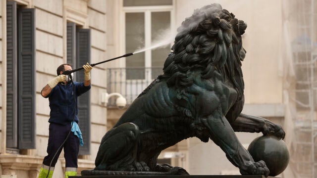 Un operario utiliza agua a presión para limpiar uno de los leones del Congreso, este martes | Fuente: EFE/ Chema Moya