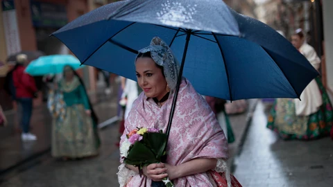 Una fallera se protege de la lluvia con un paraguas a falta de dos días y medio para que acaben las Fallas de 2022