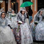 Unas falleras se protegen de la lluvia con chubasqueros durante el principal acto devoto de las Fallas, la Ofrenda floral, a la que más de 93.000 miembros de todas las edades de las 383 comisiones falleras de València están llamados a participar este año