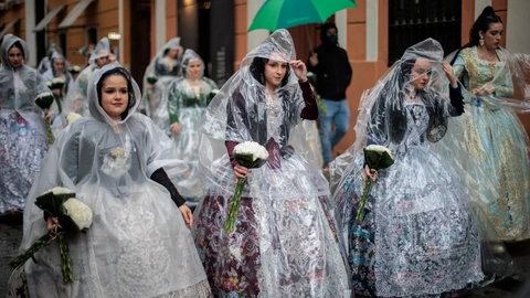 Unas falleras se protegen de la lluvia con chubasqueros durante el principal acto devoto de las Fallas, la Ofrenda floral, a la que más de 93.000 miembros de todas las edades de las 383 comisiones falleras de València están llamados a participar este año