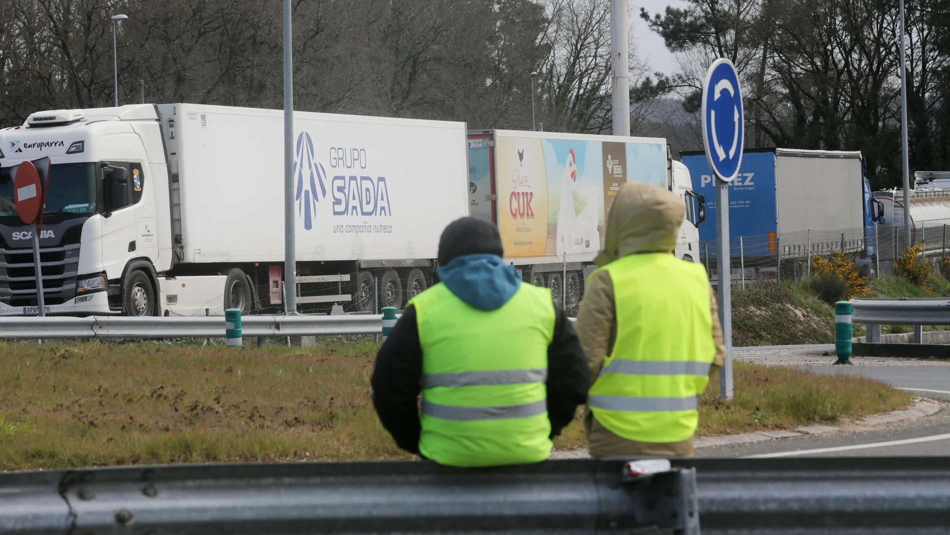 Dos miembros de un piquete observan los camiones estacionados en una rotonda de O Corgo (Lugo), durante el cuarto día de paros en el sector de los transportes, a 17 de marzo de 2022