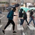 Varias personas se resguardan de la lluvia este jueves en la Gran Vía de Murcia